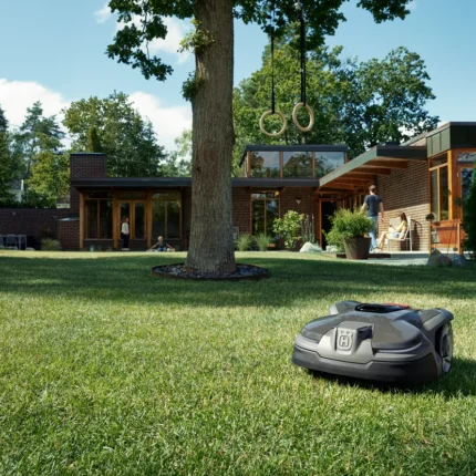 Mähroboter in einem Garten mit einem modernen Haus im Hintergrund.