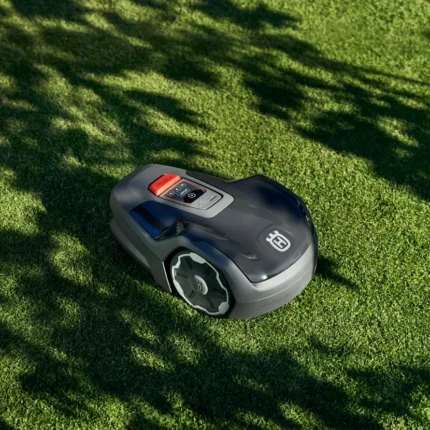 Mähroboter, der auf einem gepflegten Rasen mit Schatten der Bäume arbeitet.