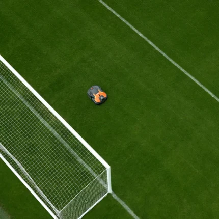 Mähroboter, der auf einem Fußballfeld in der Nähe eines Torpfostens arbeitet.
