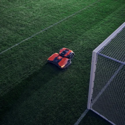 Mähroboter, der auf einem Fußballfeld in der Nähe eines Torpfostens arbeitet.